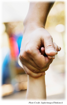 A close-up of an adult holding a child’s hand