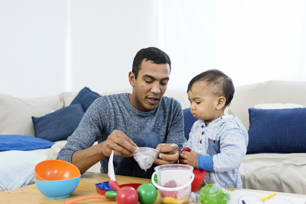 Father with baby sitting in the livingroom and having fun together