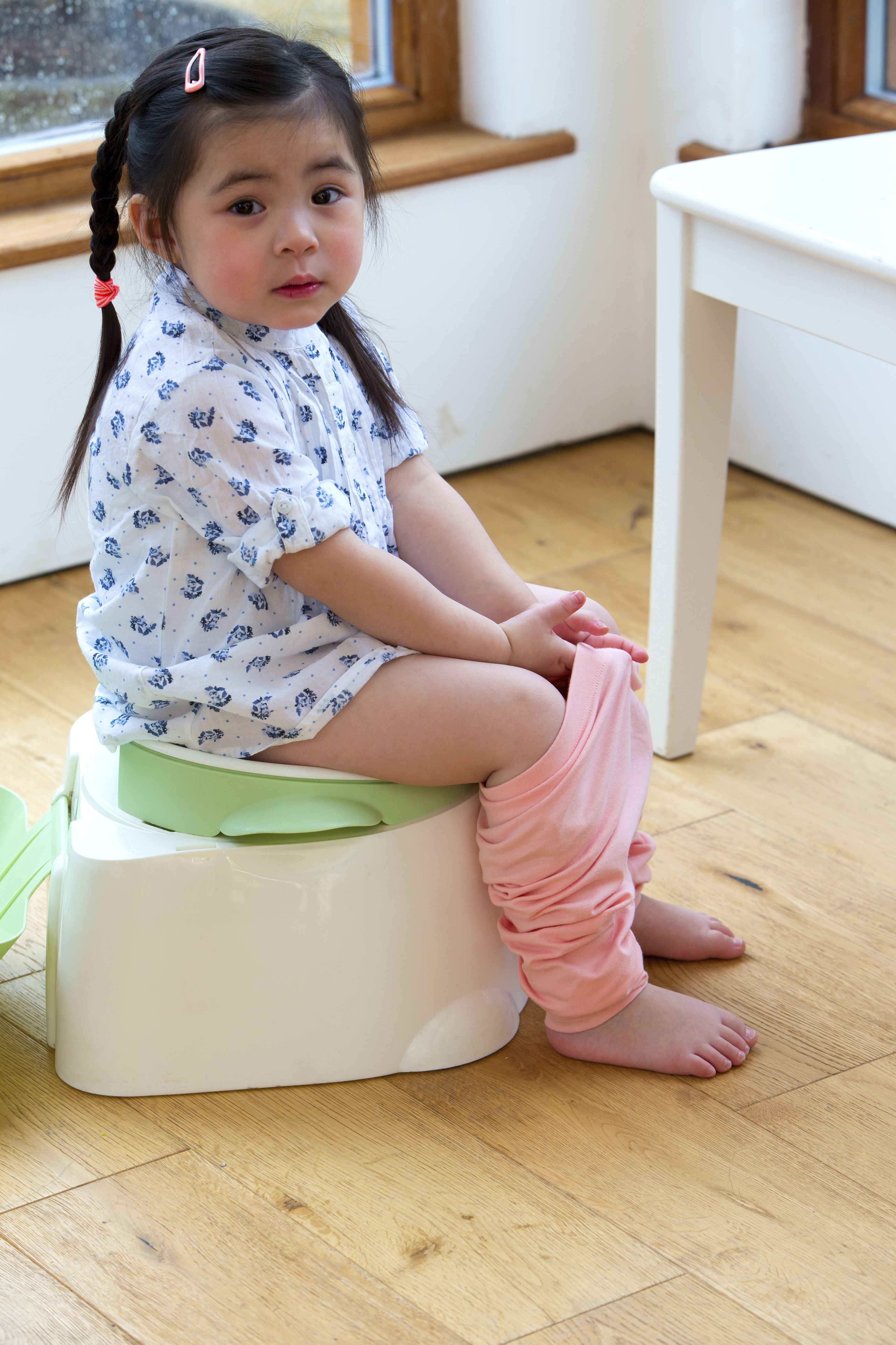 18 to 36 months has a toddler girl sitting on a small toilet