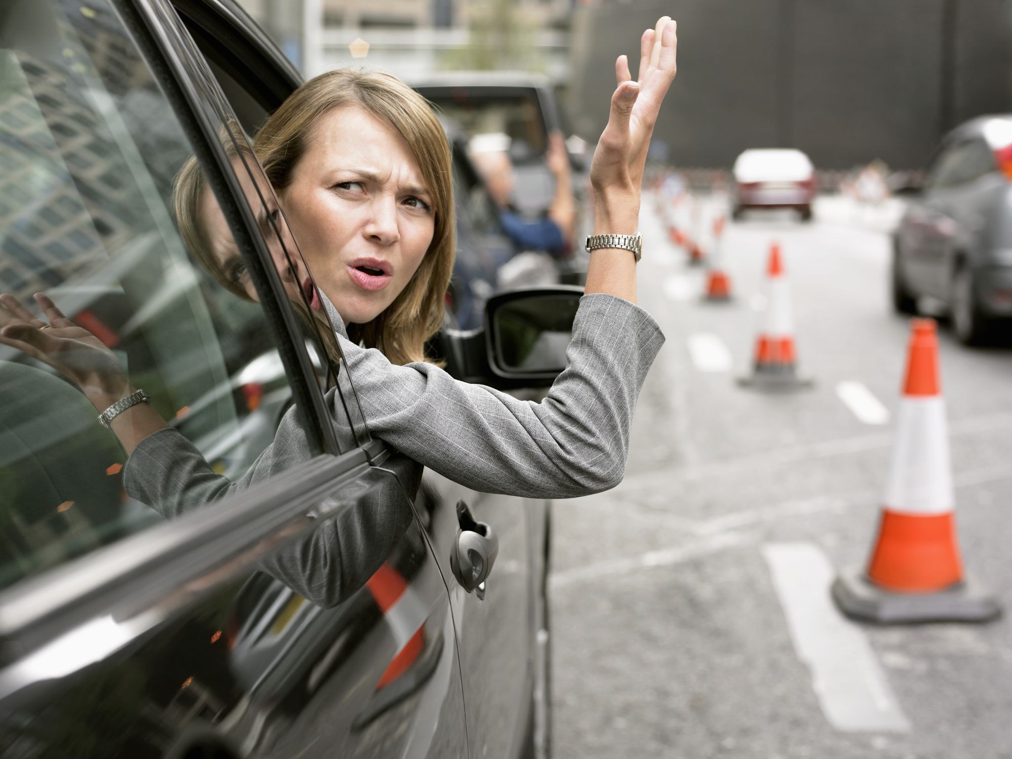 Photo of a frustrated driver performing an angry, aggressive, or rude gesture, with accompanying facial expression or anger or hostility or threat