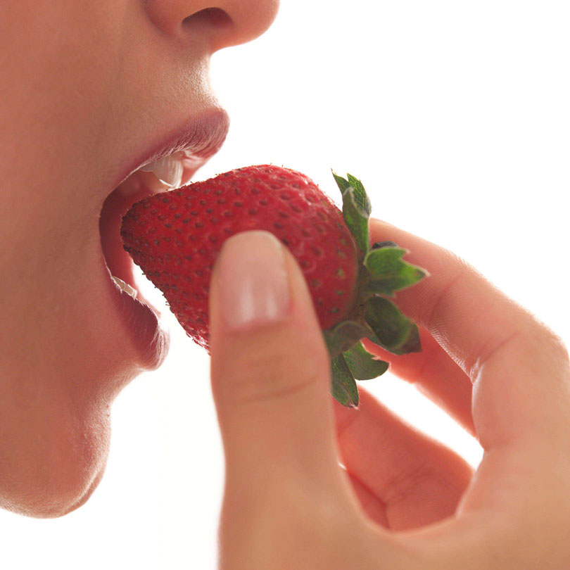 Photo: Close-up photo of a person eating a distinctive and attractive food, such as a strawberry