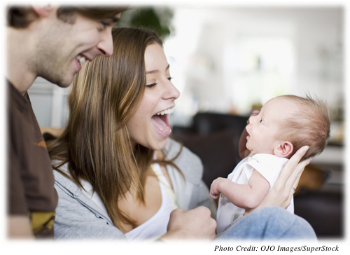 Couple smiling and laughing while holding their newborn