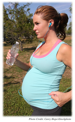 A pregnant woman, who may be in her second trimester, is power walking.