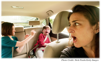 A mother driving a car who is yelling at her two children fighting in the back seat.