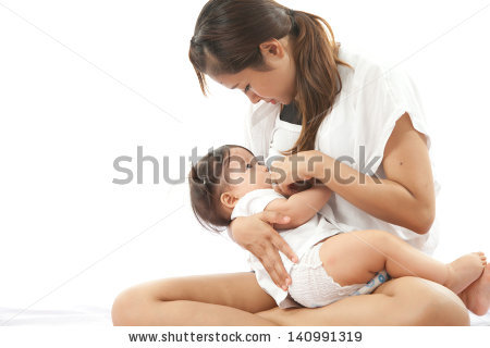 Color image of woman sitting cross-legged while she breast-feeds her baby.