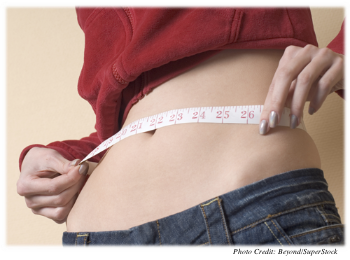 A dangerously thin woman is measuring her waist with a tape measure