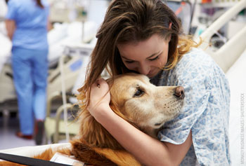 Picture of a girl in a hospital hugging a dog