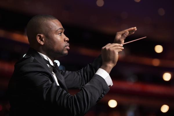 Photo shows the conductor of an orchestra to signify that his leadership qualities are different from other employees.