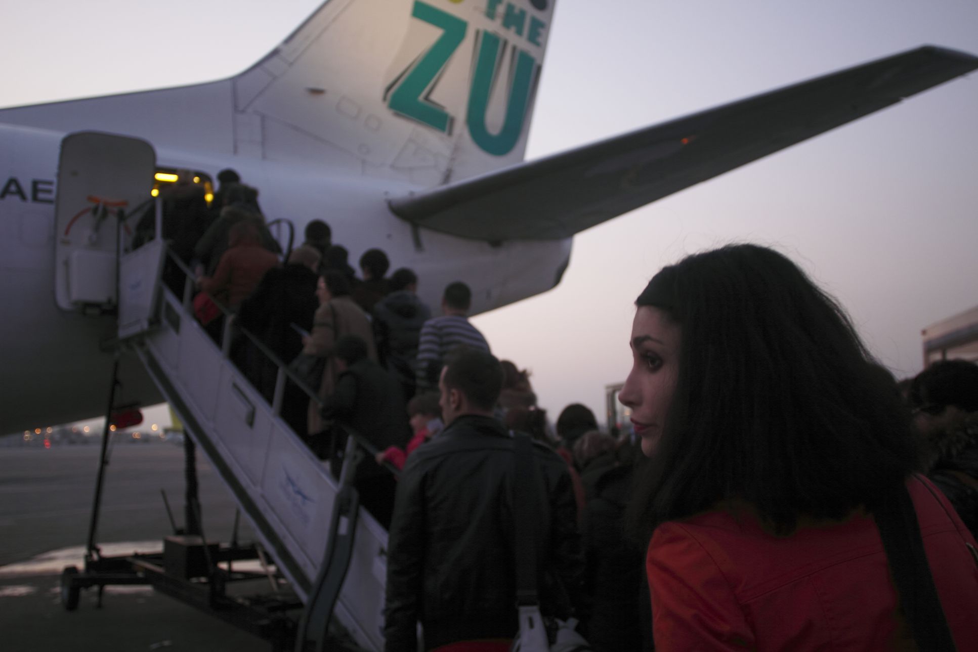 A woman stands in line to board an airplane, indicating the stressful experience of flying. 