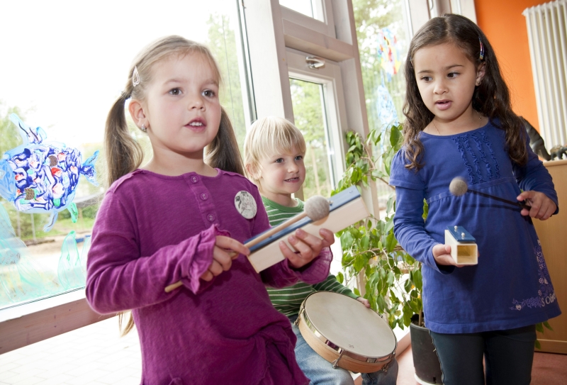 A group of kindergarten students play musical instruments, which helps in developing their interaction with each other. 