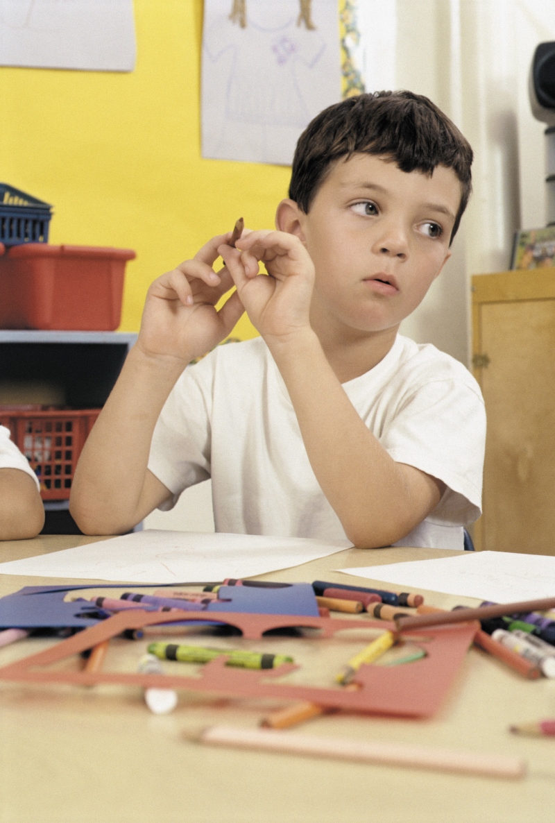A child looks away from the task he is working on. His looking away indicates that young children distract easily from tasks. 