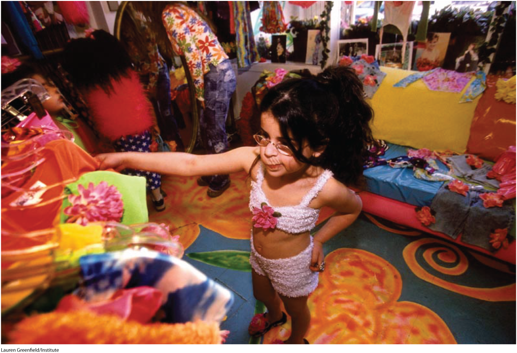 A photo shows a small girl choosing a dress from a colorful wardrobe.