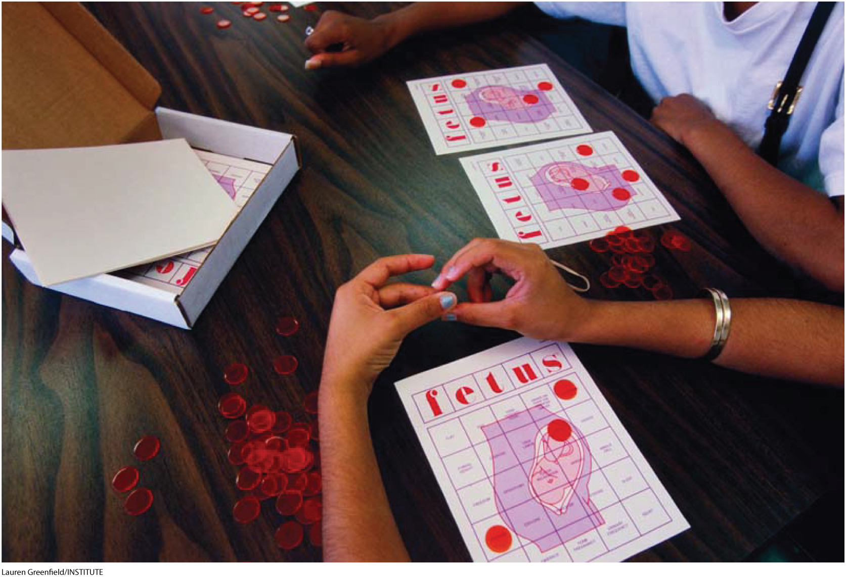 A photo shows people playing a board game like Bingo, except this one is called Fetus.