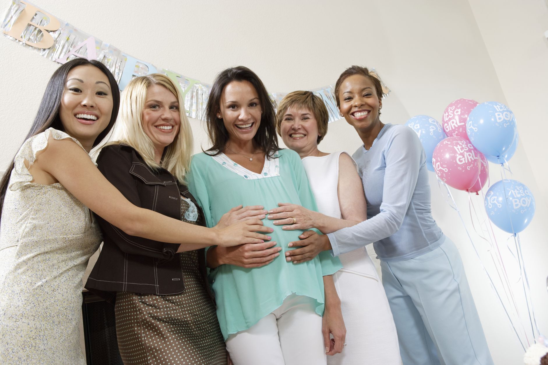 A pregnant woman surrounded by friends at her baby shower.