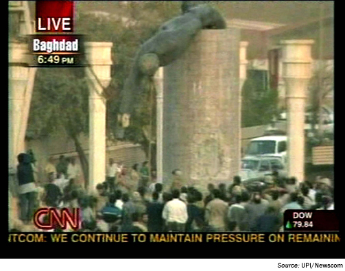 Images. A frame of a TV broadcast showing a closeup of a crowd gathered around a large column. A statue from the top of the column is being lowered down to the ground. Source U P I / Newscom.
