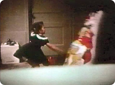 A young girl hits doll with a hammer.