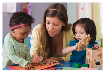 A caregiver engaged closely with two young girls – one girl is coloring and the other is playing with blocks and shapes.
