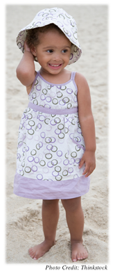 A young girl smiling and standing on a beach