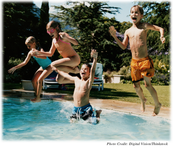 Two young boys and two young girls leaping into a swimming pool