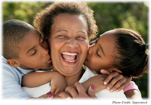 Older woman smiling and being kissed by her grandchildren