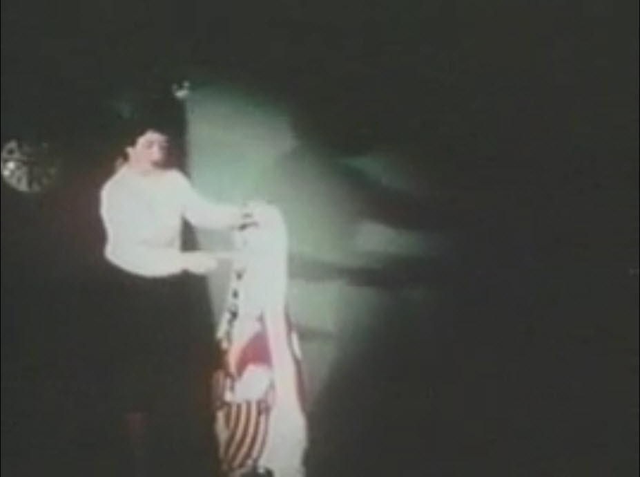 The image is a still photo of a video showing a woman punching a Bobo doll.