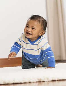 Mixed race baby boy crawling on carpet