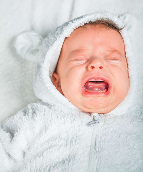 Portrait of a 2 months old baby boy crying outloud.
