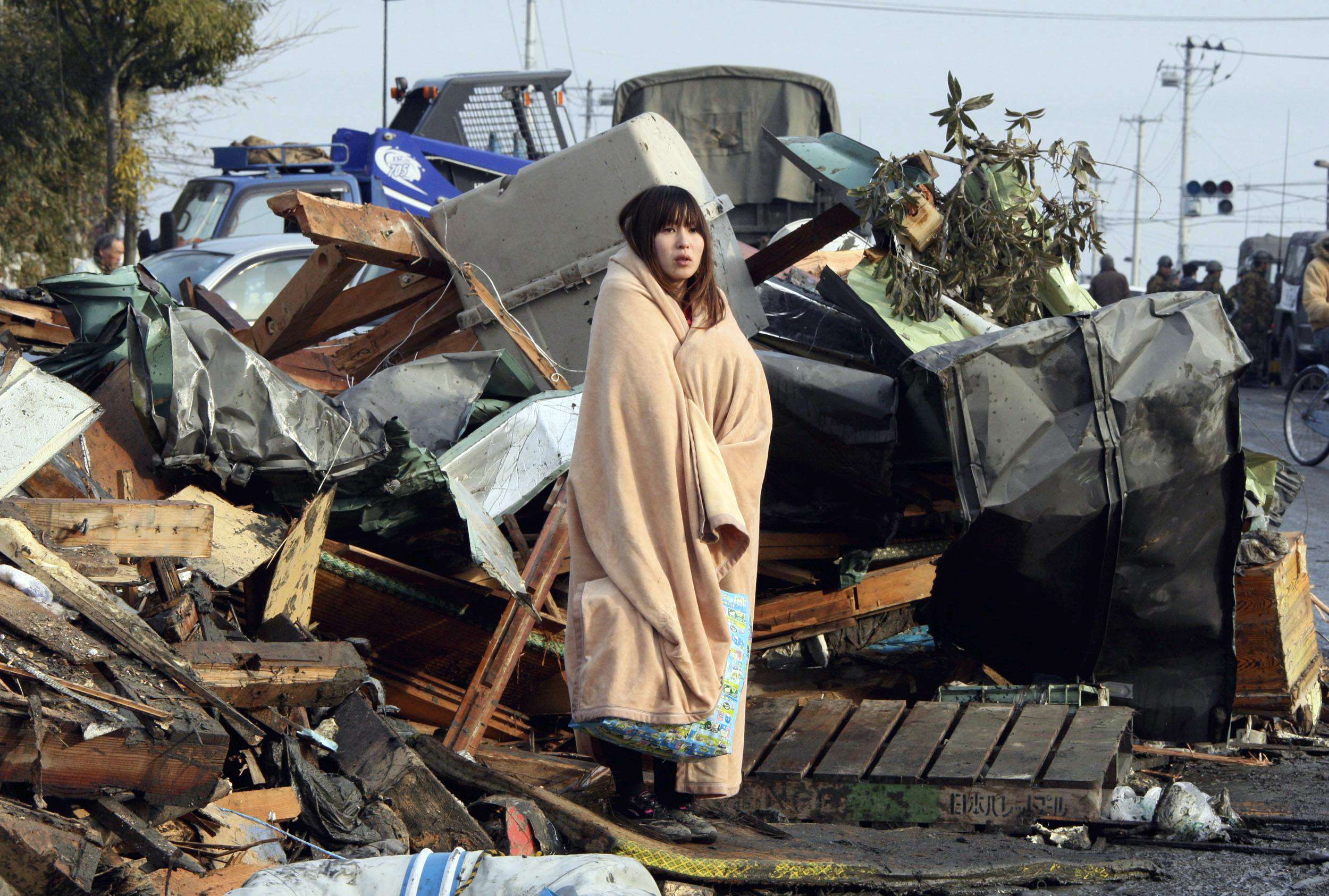 Photo of single individual at scene of natural disaster; individual appears to be in shock