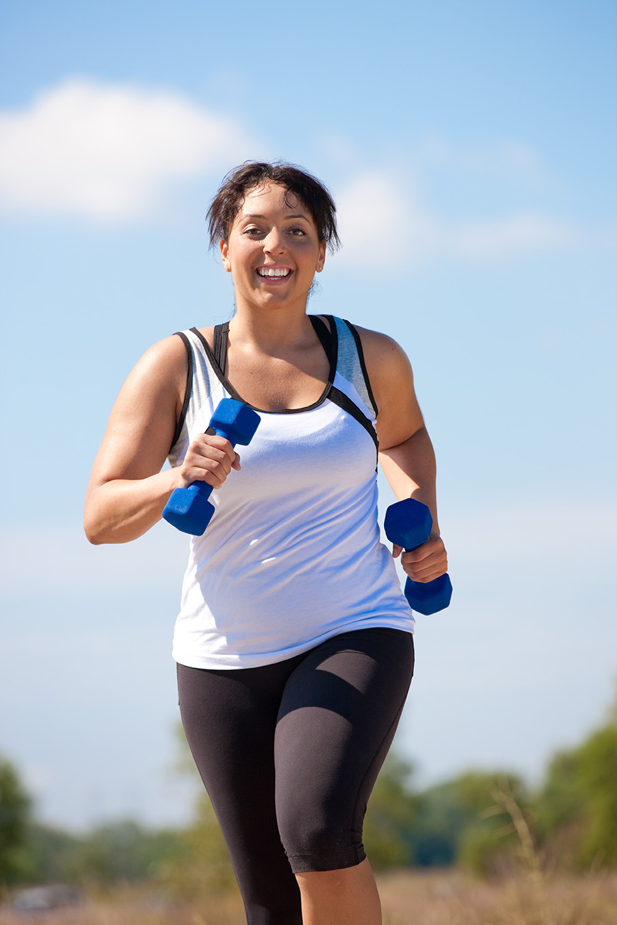 Color image of a smiling woman running with weights.