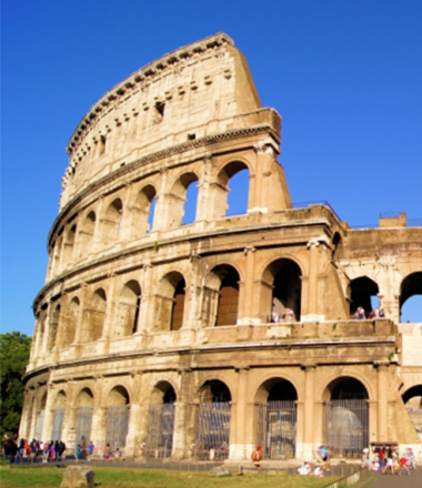 Groups of tourists walk around the base of the Roman Colosseum.