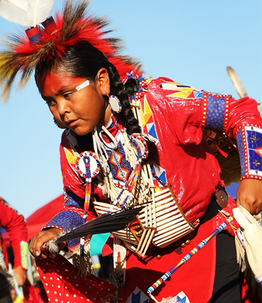 A tribal woman wearing bright colored clothes performing a traditional dance ritual.