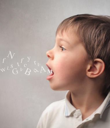 Side view of a young boy with his mouth open and alphabet flying out of his mouth.