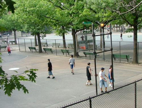 Basketball players walk on an outdoor court after the ball is dropped in the basket.