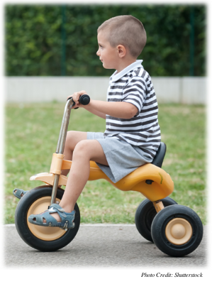 A young boy riding a tricycle