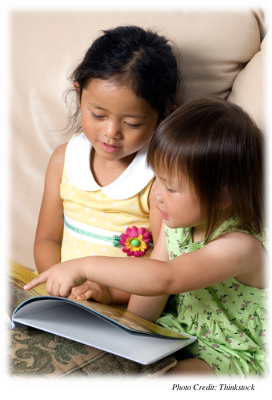 Two young girls looking at a book together