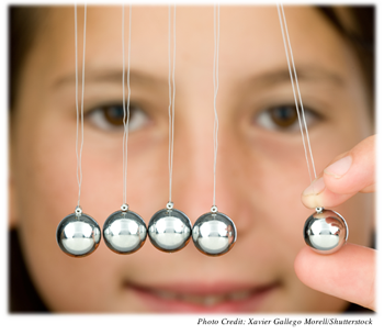 A young girl staring at a shot put pendulum