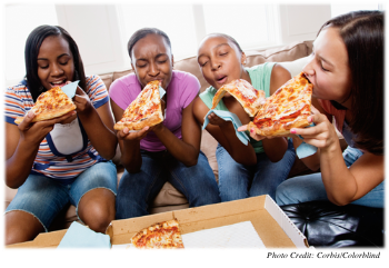 Four teenage girls enjoying pizza
