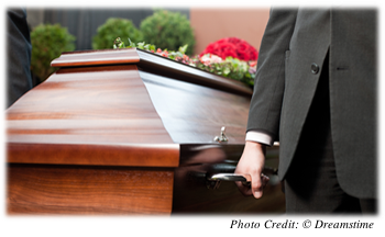 A close-up of a coffin being carried by a pallbearer