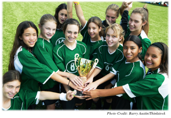 Eleven teenage girls from an athletic team all holding a trophy while looking excited and happy  