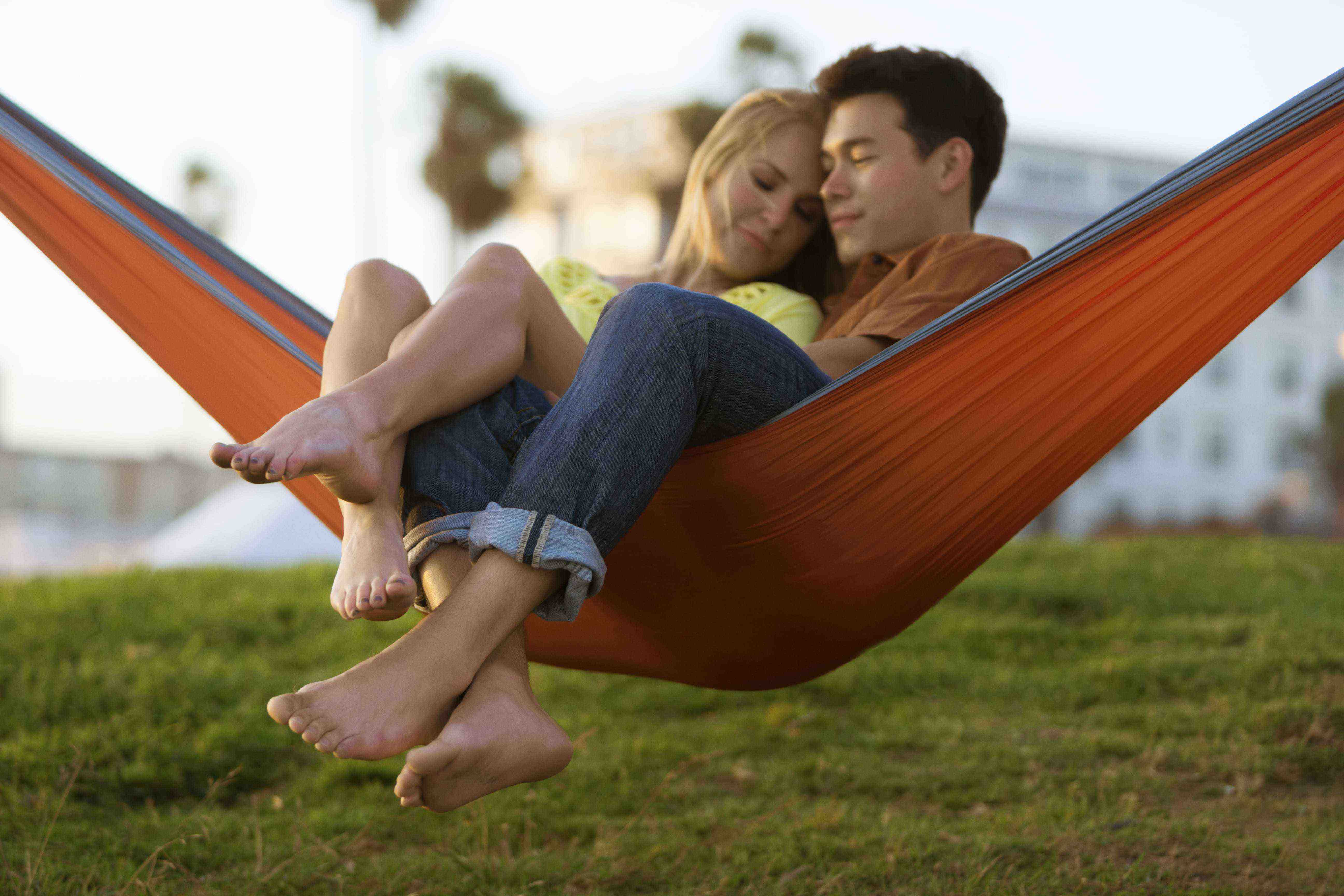 A man and woman are snuggling in a hammock