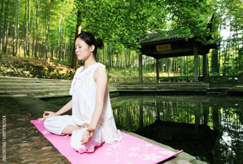 Picture of a woman meditating near a pond