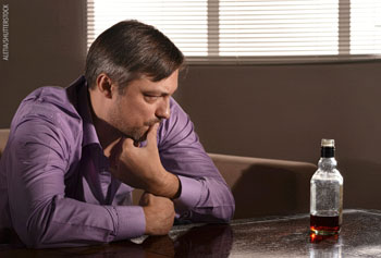 Picture of a man looking at a bottle of alchohol