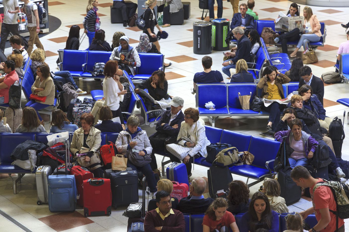 Photo shows a group of people in a waiting room of an airport, which signifies the stressful experience that many associate with flying.