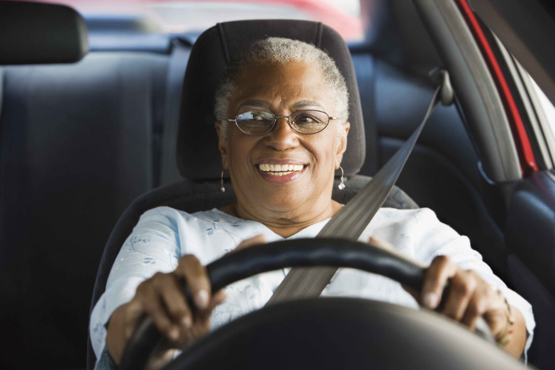 An elderly female drives her car, which signifies her skill.