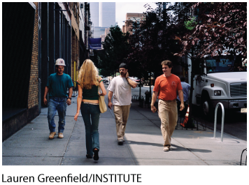A photo shows the back view of a woman walking on a street and three men walking opposite to her while looking at her.