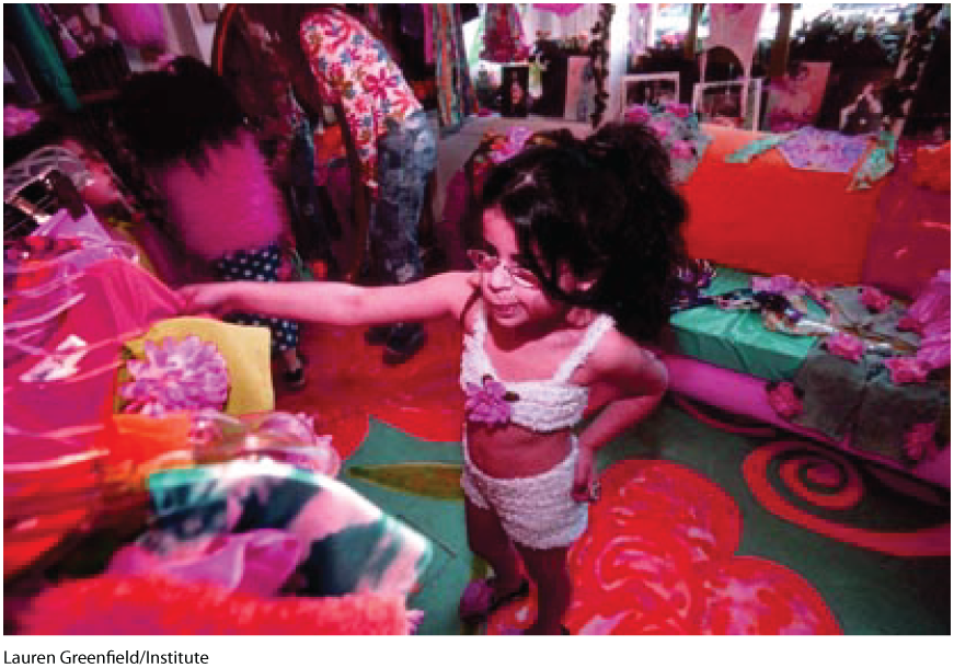 A pink tinted photo shows a small girl choosing a dress from a wardrobe.