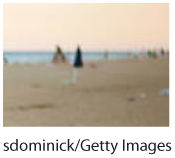 A cropped photo of the sandy beach and the sea. The trash is not visible.