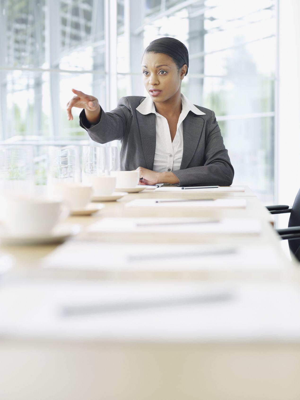 A woman at a conference table points to a colleague.