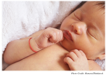 Newborn asleep on its back with arms and hands curled up near face