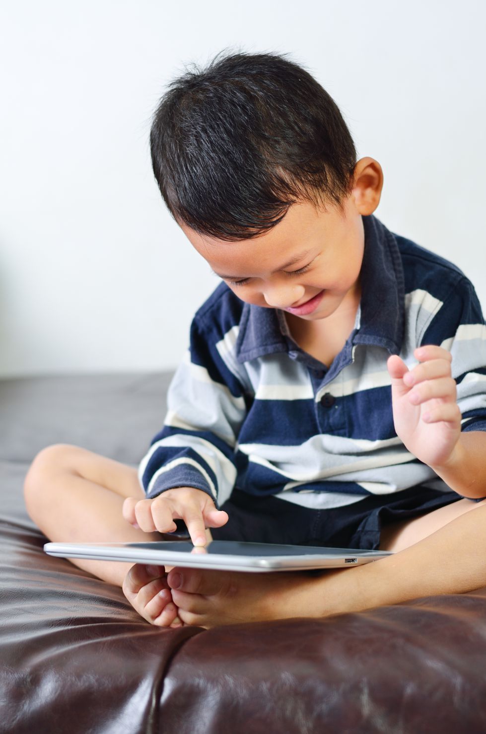 A smiling little boy using his tablet.